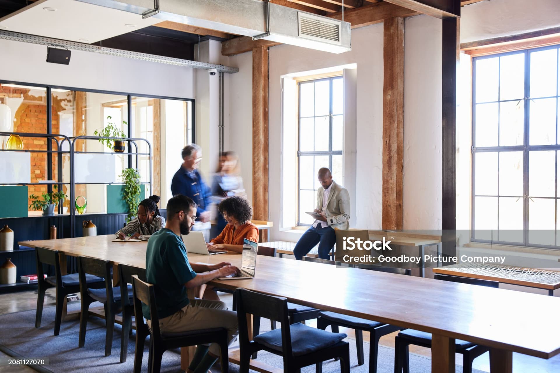 Modern coworking space with people working at shared tables